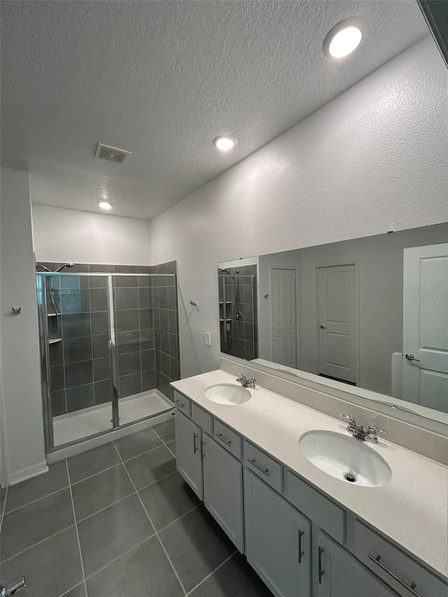 bathroom with vanity, a textured ceiling, tile patterned flooring, and a tile shower