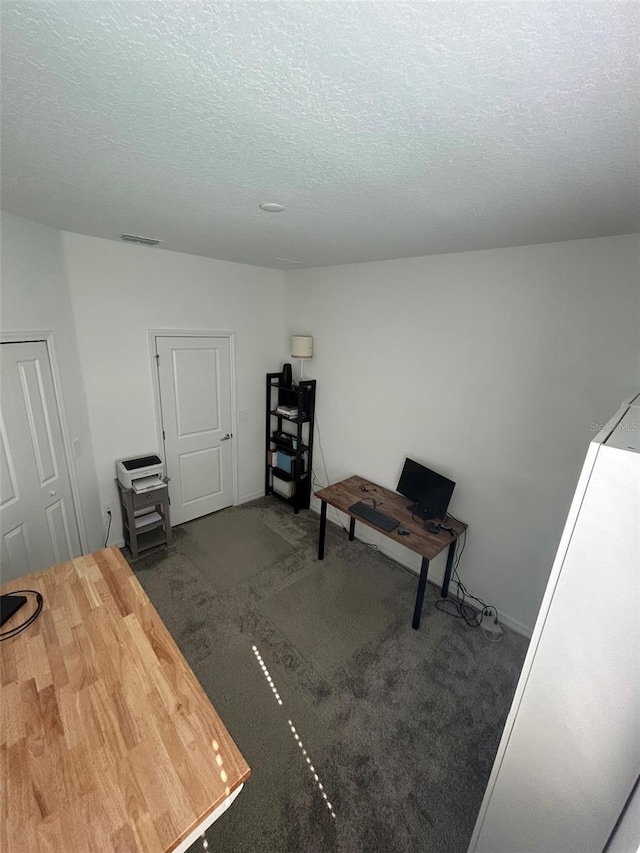 miscellaneous room with dark colored carpet and a textured ceiling