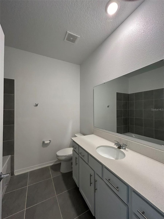 bathroom featuring vanity, a textured ceiling, tile patterned floors, and toilet