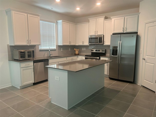 kitchen featuring appliances with stainless steel finishes, decorative backsplash, sink, tile patterned flooring, and white cabinets