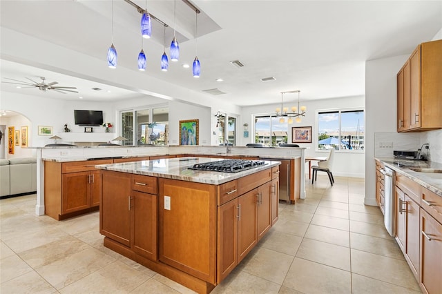 kitchen with decorative light fixtures, light stone countertops, appliances with stainless steel finishes, ceiling fan, and a large island