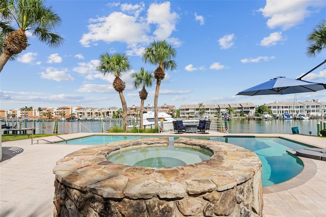 view of pool featuring a water view and an in ground hot tub