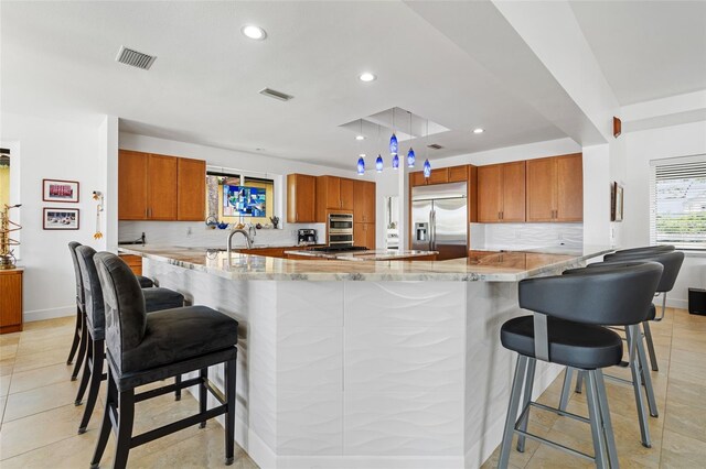 kitchen with light stone counters, kitchen peninsula, stainless steel appliances, and decorative backsplash