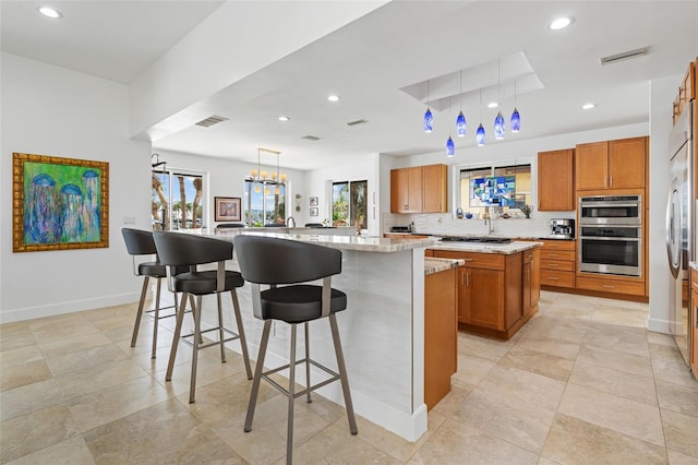 kitchen with a breakfast bar area, light stone countertops, a spacious island, pendant lighting, and tasteful backsplash