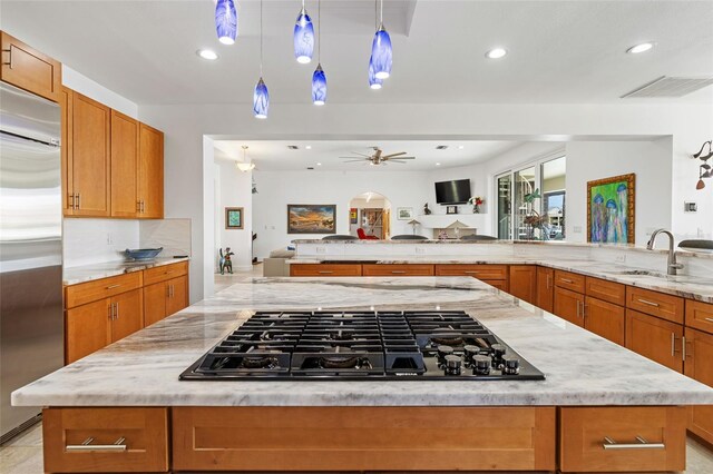 kitchen featuring appliances with stainless steel finishes, a center island, ceiling fan, and hanging light fixtures