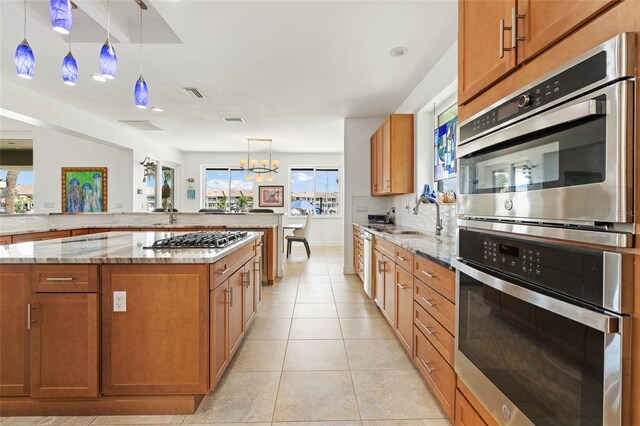 kitchen featuring pendant lighting, stainless steel appliances, a healthy amount of sunlight, and a center island