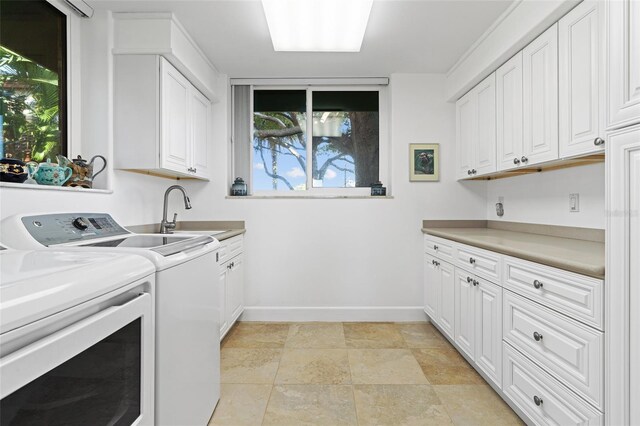 washroom with cabinets, washing machine and dryer, and sink