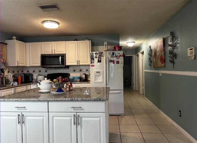 kitchen with backsplash, a textured ceiling, white refrigerator with ice dispenser, white cabinetry, and light tile patterned flooring