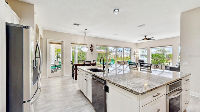 kitchen with stainless steel refrigerator with ice dispenser, sink, white cabinetry, dishwasher, and an island with sink