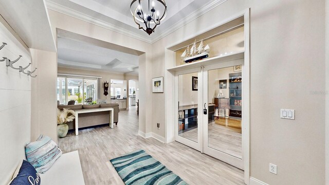 interior space featuring hardwood / wood-style floors, a notable chandelier, a tray ceiling, crown molding, and french doors