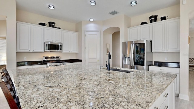 kitchen featuring sink, light stone countertops, white cabinets, and appliances with stainless steel finishes