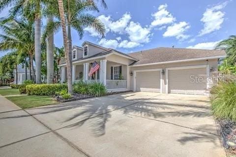 view of front of property featuring concrete driveway, an attached garage, covered porch, and stucco siding