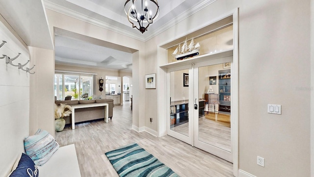 entryway with a chandelier, baseboards, crown molding, wood finished floors, and a raised ceiling
