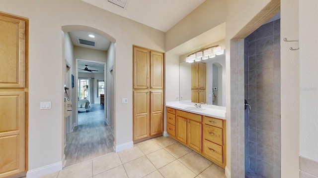 bathroom with tile patterned floors, vanity, ensuite bath, baseboards, and tiled shower