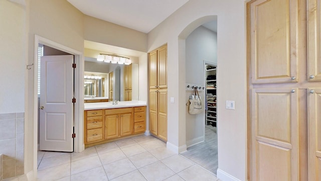 bathroom with tile patterned floors, vanity, a spacious closet, and baseboards