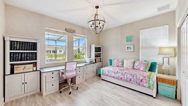 bedroom with light wood-type flooring, a chandelier, and an office area