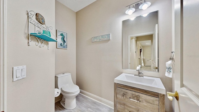 bathroom with baseboards, toilet, vanity, and wood finished floors