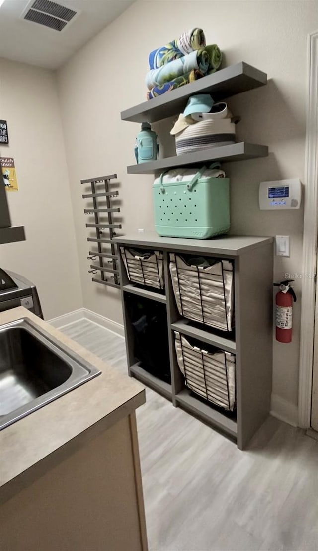 kitchen featuring light wood-style floors, baseboards, and a sink