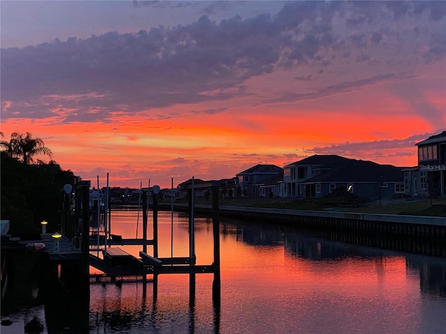 dock with boat lift, a water view, and a residential view