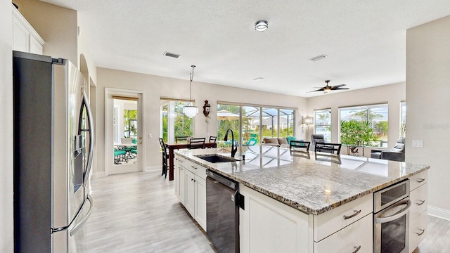 kitchen with stainless steel refrigerator with ice dispenser, black dishwasher, a sink, light wood finished floors, and baseboards