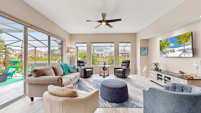 living room with a sunroom, ceiling fan, wood finished floors, and a residential view