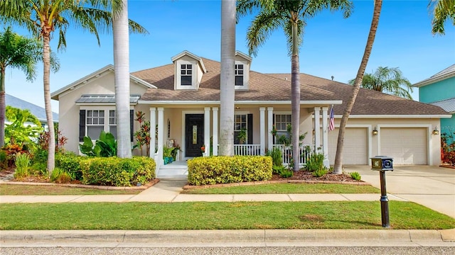 view of front facade featuring a garage, a porch, concrete driveway, stucco siding, and roof with shingles