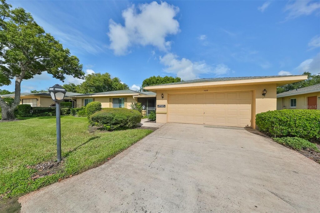 ranch-style home with a garage and a front lawn