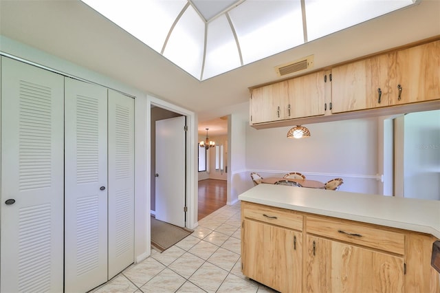 kitchen featuring light brown cabinetry, light tile patterned floors, and a notable chandelier