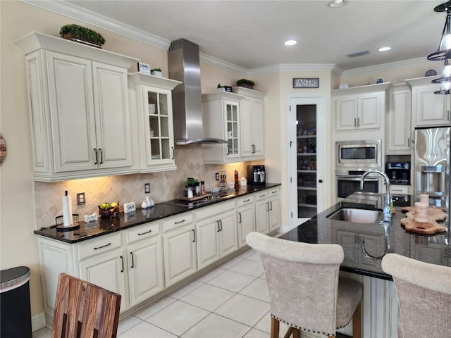 kitchen with appliances with stainless steel finishes, light tile patterned floors, white cabinets, and wall chimney range hood