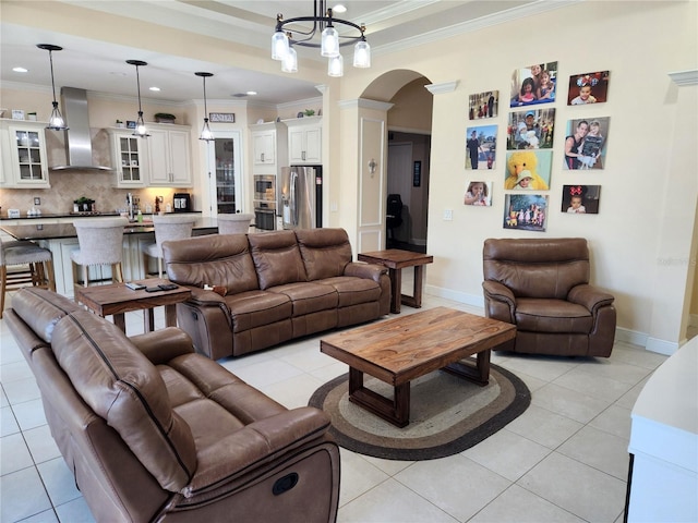 tiled living room with ornamental molding, a notable chandelier, and ornate columns