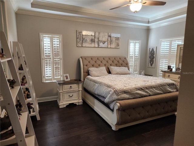 bedroom featuring dark wood-type flooring, multiple windows, ceiling fan, and a raised ceiling