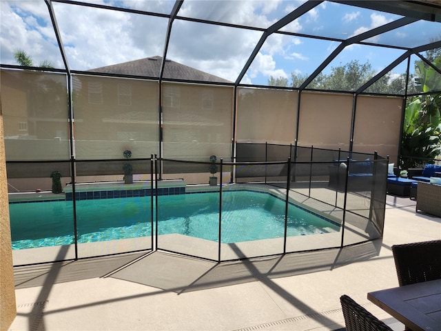 view of pool with glass enclosure and a patio area