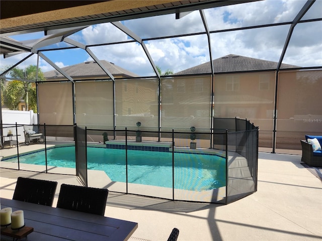 view of pool with glass enclosure and a patio area