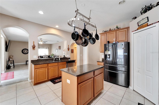 kitchen with a center island, stainless steel appliances, sink, ceiling fan, and dark stone countertops