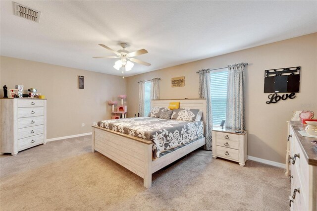 bedroom with multiple windows, ceiling fan, and light carpet