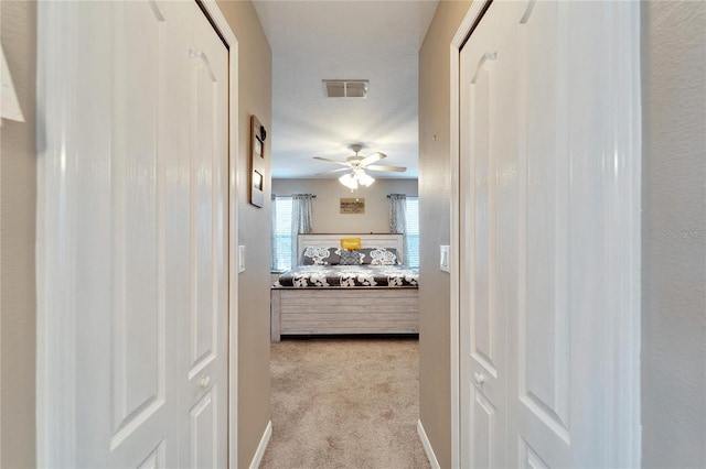 hall featuring a textured ceiling and light colored carpet