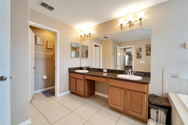 bathroom featuring a textured ceiling, vanity, a bathtub, and tile patterned floors