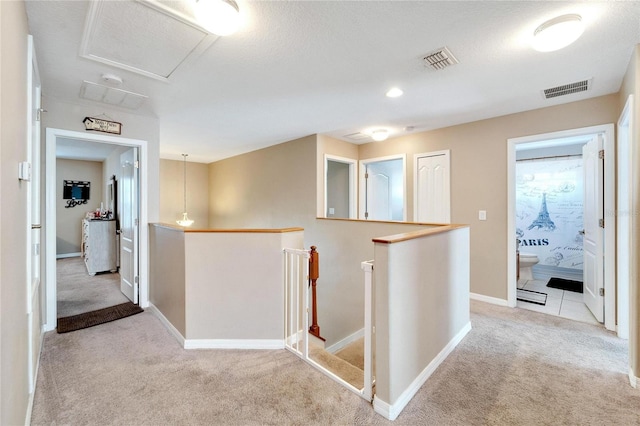 corridor with light colored carpet and a textured ceiling