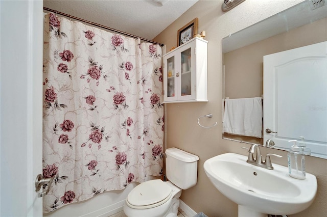 full bathroom featuring a textured ceiling, toilet, sink, and shower / bath combo