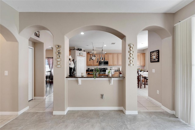 kitchen with a kitchen bar, stainless steel appliances, kitchen peninsula, and light tile patterned flooring