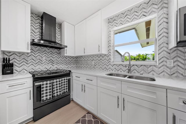 kitchen featuring electric range, a sink, tasteful backsplash, white cabinetry, and wall chimney range hood