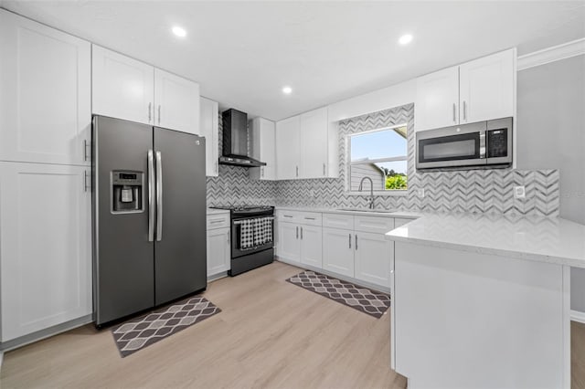 kitchen featuring a sink, stainless steel appliances, wall chimney exhaust hood, white cabinets, and light wood finished floors