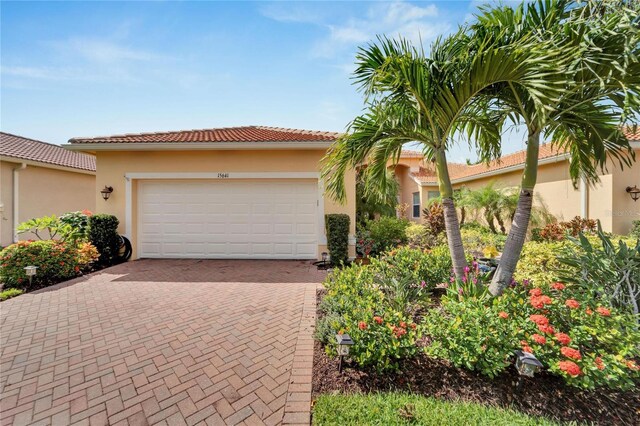 view of front of house with a garage, a tile roof, decorative driveway, and stucco siding