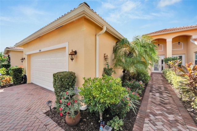 garage with decorative driveway and french doors