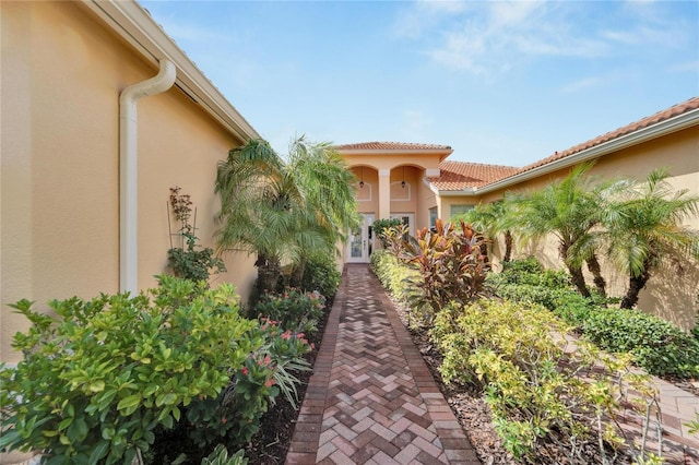 entrance to property featuring a tile roof, french doors, and stucco siding