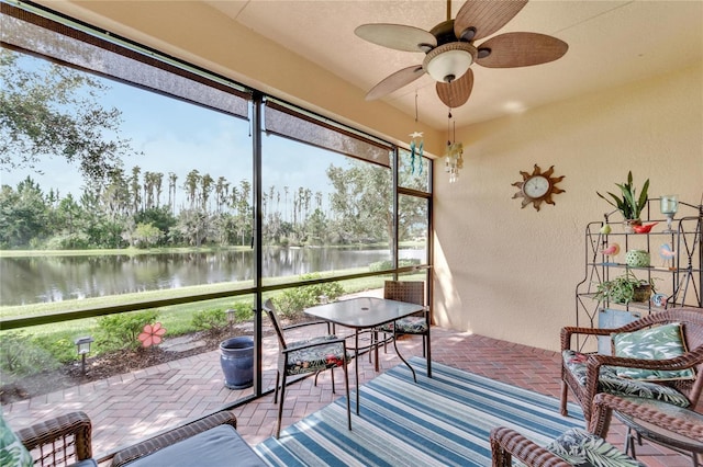 sunroom featuring a water view and ceiling fan