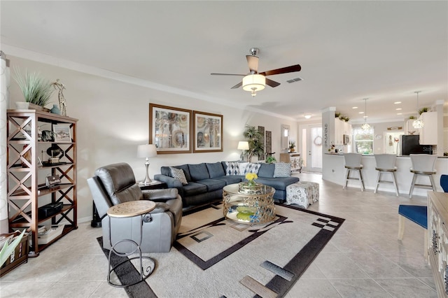 living room featuring light tile patterned flooring, crown molding, baseboards, and ceiling fan