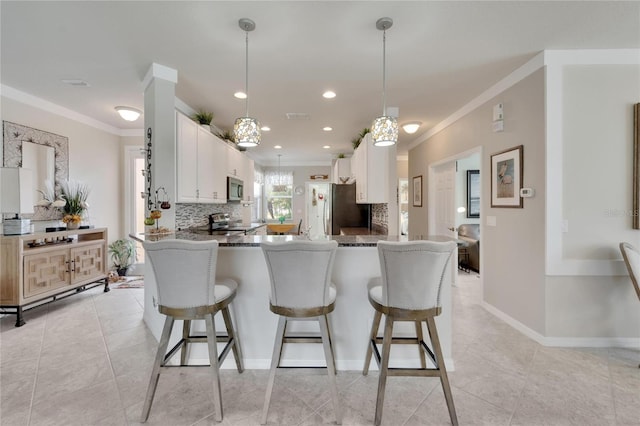 kitchen with tasteful backsplash, hanging light fixtures, kitchen peninsula, stainless steel appliances, and white cabinetry