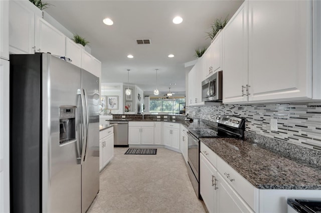 kitchen featuring white cabinets, hanging light fixtures, stainless steel appliances, kitchen peninsula, and decorative backsplash