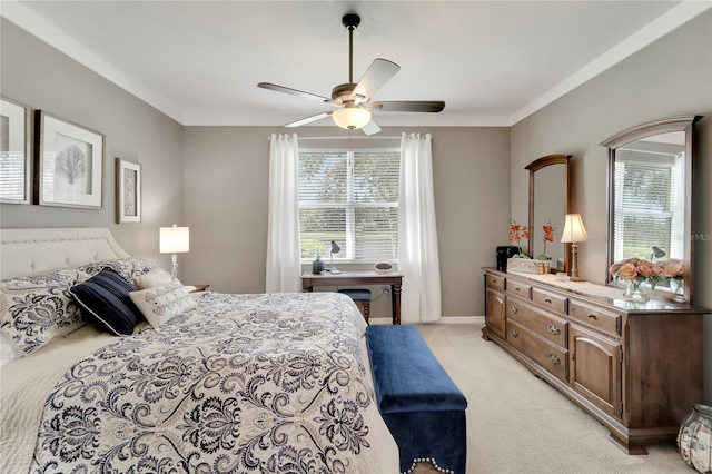 bedroom featuring light carpet, ornamental molding, and a ceiling fan